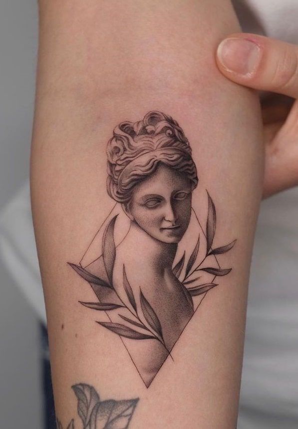 a woman's arm with a tattoo on it and leaves around the arm area