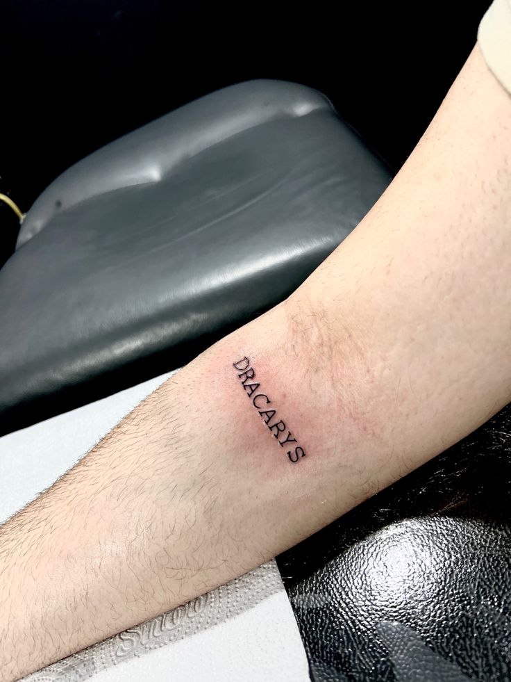 a man with a tattoo on his arm that reads, dance and is sitting in front of a chair