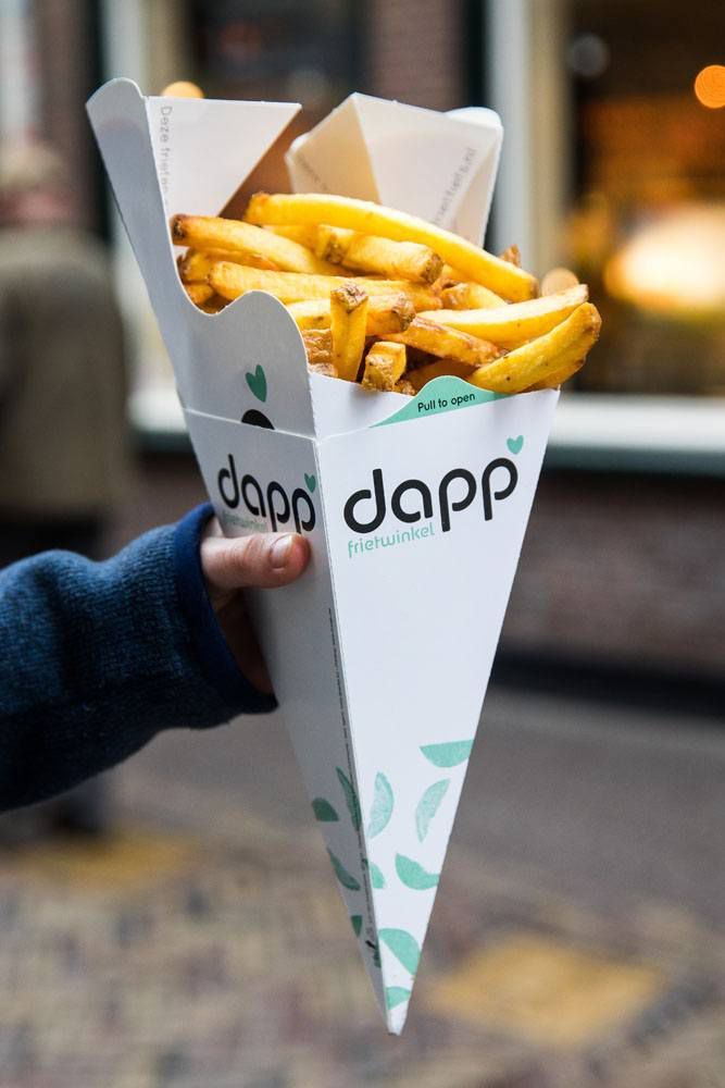 a person holding up a paper cone with french fries in it and the word dapp written on it