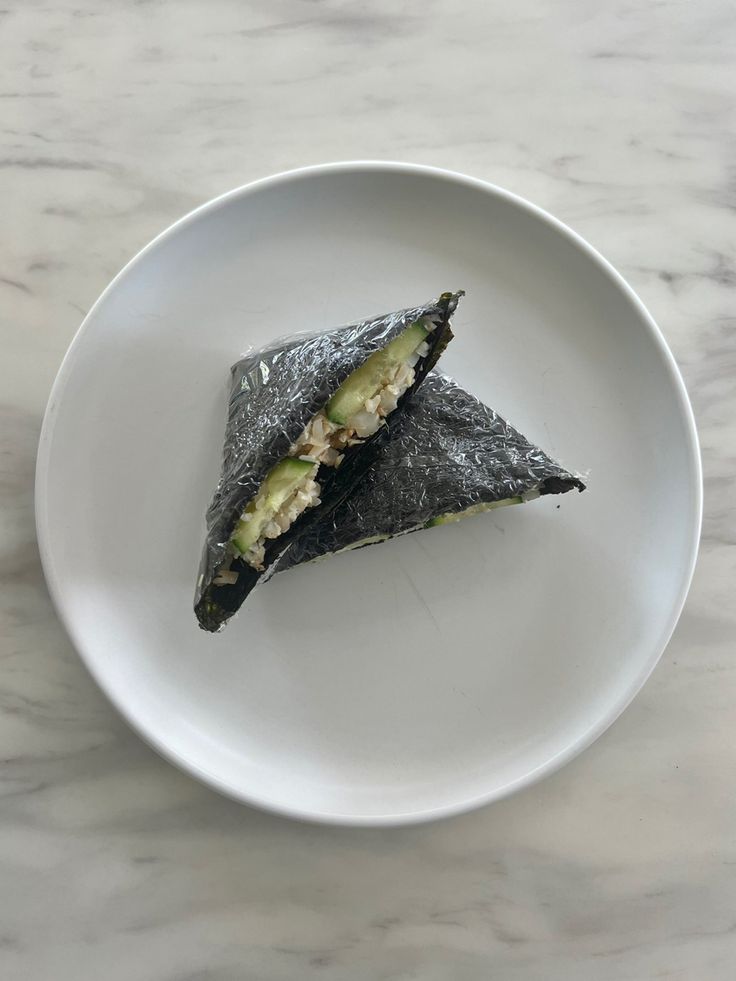 a white plate topped with an avocado wrap on top of a marble counter