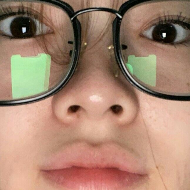 a close up of a person wearing glasses with green stickers on their eyes and nose