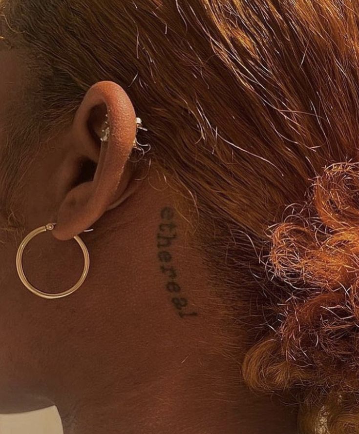 a close up of a person with a tattoo on their ear and behind her ear