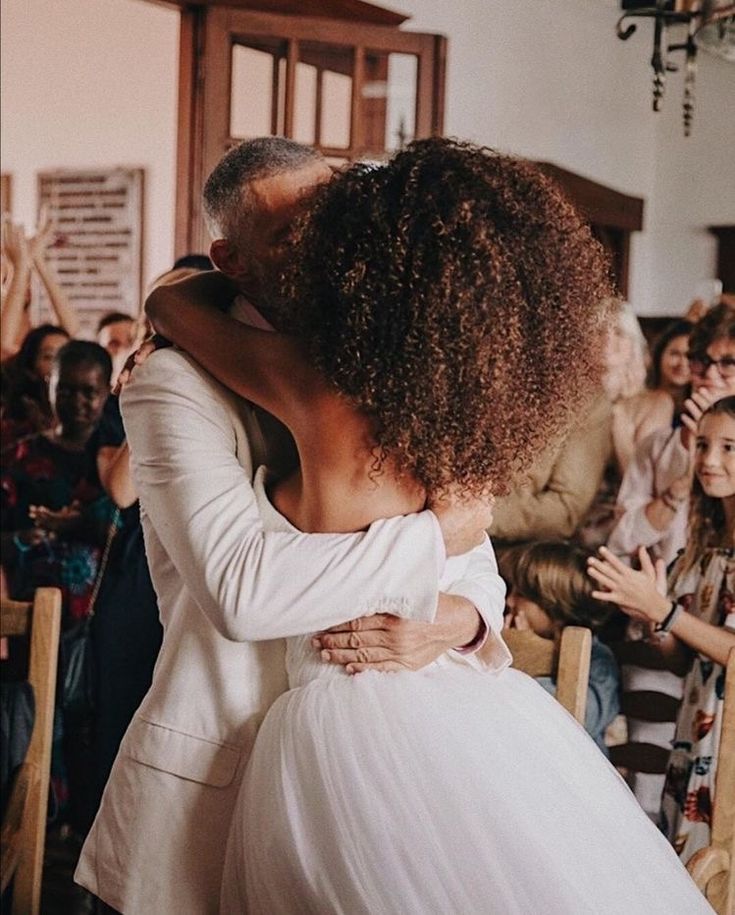 a bride and groom hug each other in front of an audience