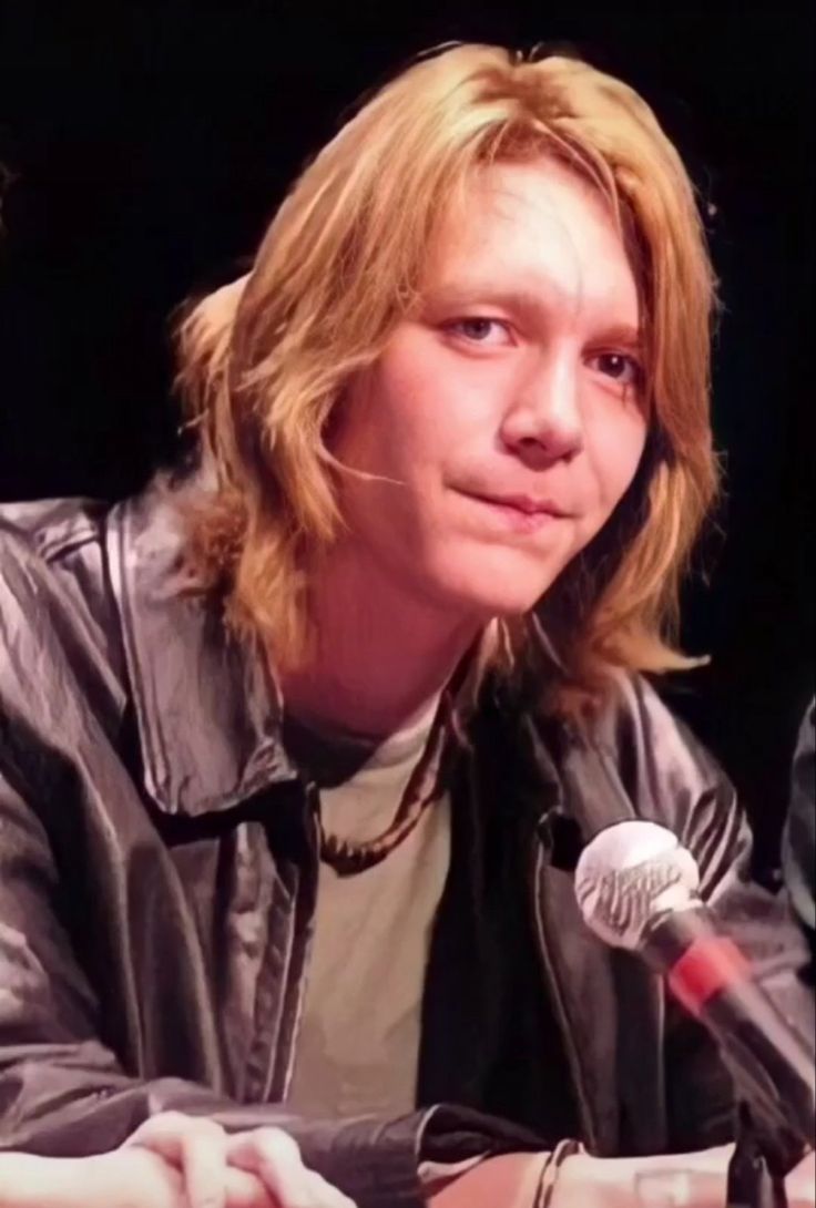 a man sitting at a table with a microphone in front of him and looking off to the side