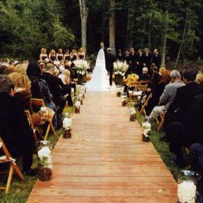 a wedding ceremony in the woods with lots of people sitting on chairs and looking at each other