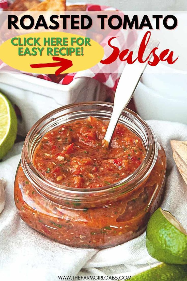 a jar filled with salsa sitting on top of a table next to limes and tortilla chips