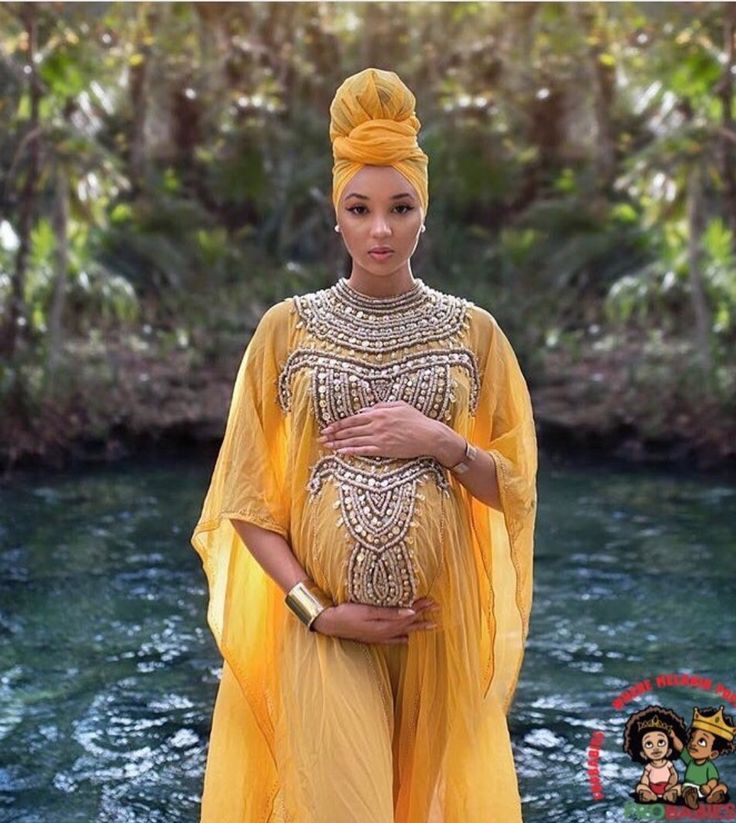 a pregnant woman in a yellow dress standing next to a river