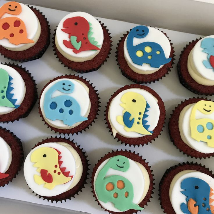 a box filled with cupcakes decorated to look like different types of dino animals