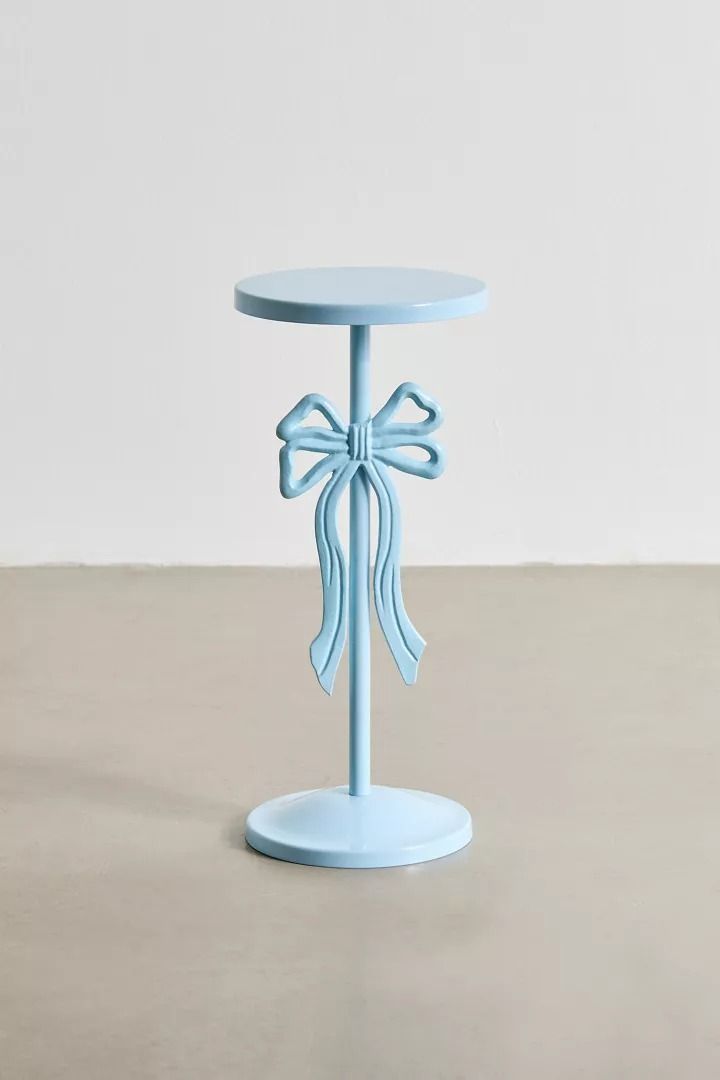 a small blue table with a bow on it's top, sitting on the floor