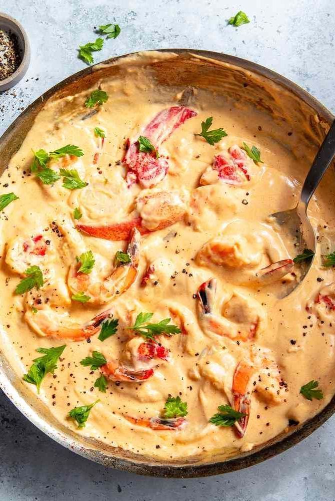 a skillet filled with shrimp and cream sauce on top of a blue countertop