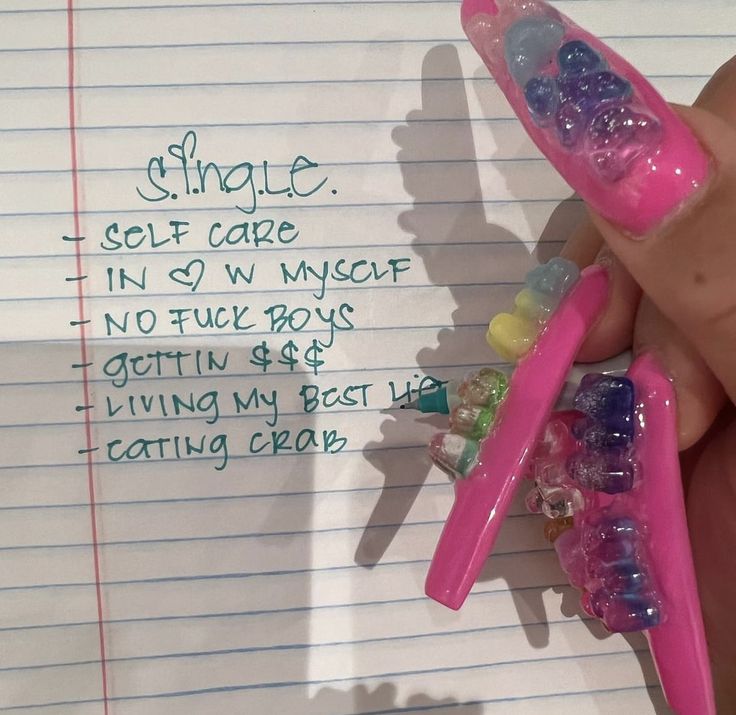 a person holding two pink toothbrushes with gummy bears on them and writing