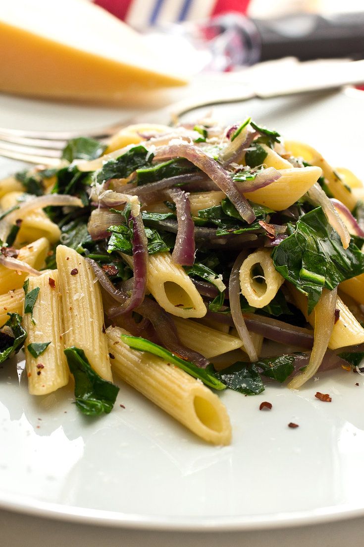 a white plate topped with pasta and greens