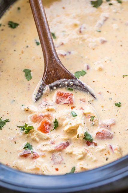 a wooden spoon in a slow cooker filled with creamy chicken and tortilla soup