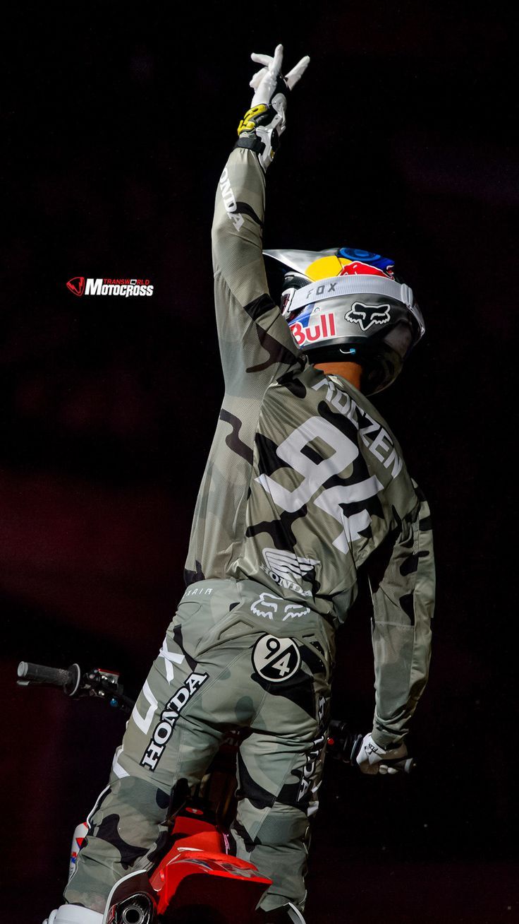 a man riding on the back of a red dirt bike in front of a black background