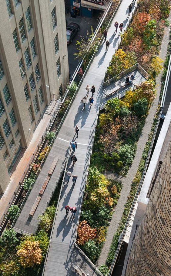 an aerial view of people walking and skateboarding on the sidewalk in front of tall buildings