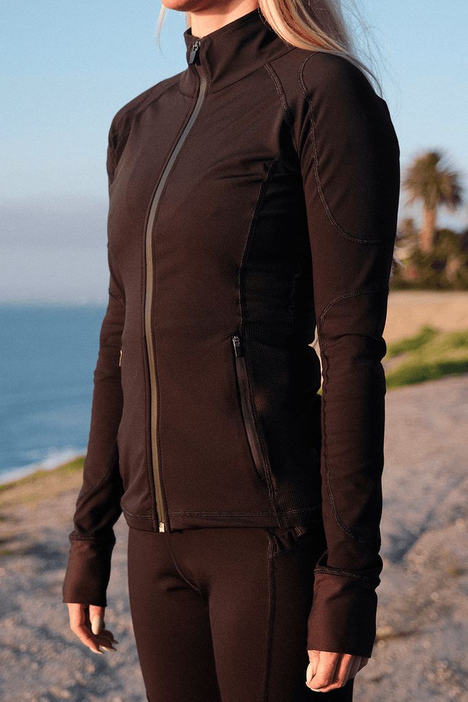 a woman standing on the beach wearing a wet suit with zippered sleeves and zips