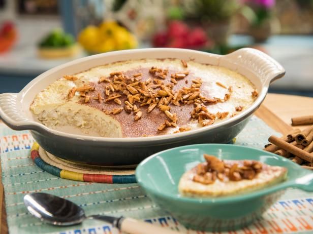 a casserole dish with nuts on top and cinnamon sticks in the bowl next to it