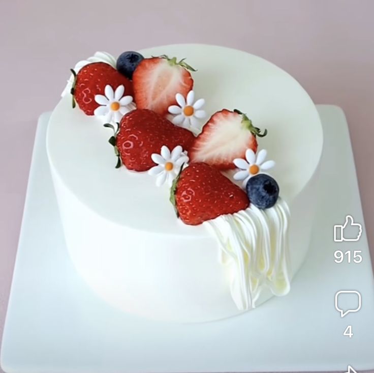 a white cake with strawberries and blueberries on top