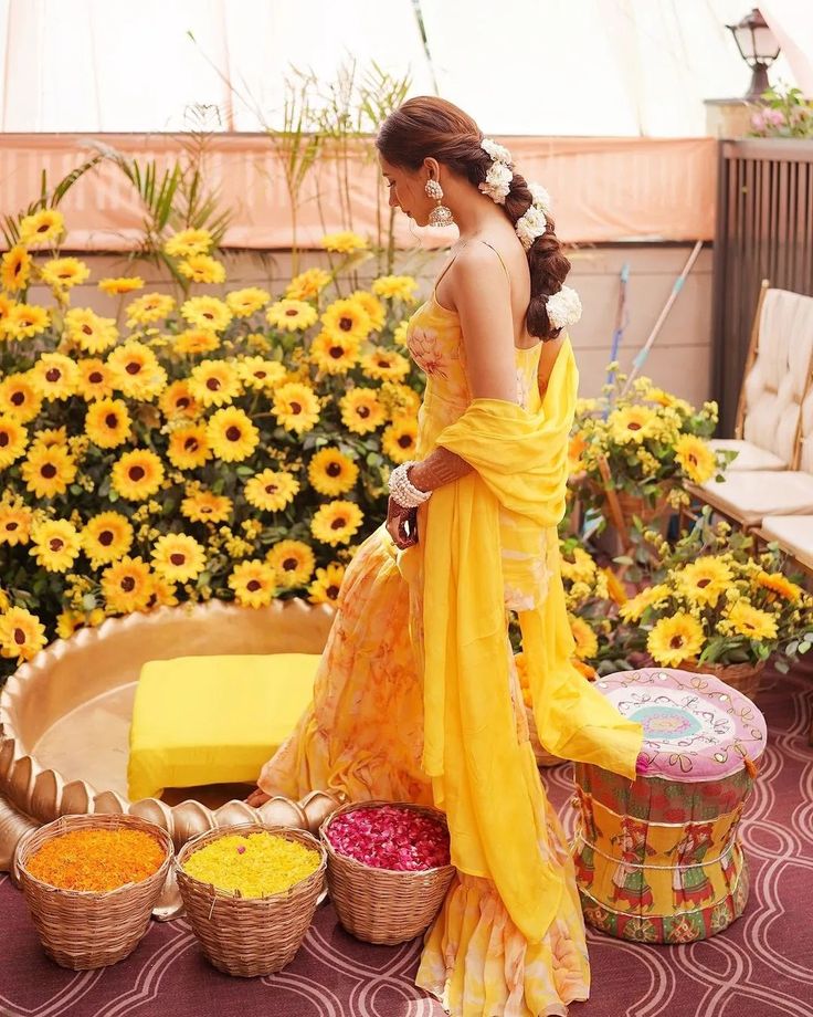 a woman in a yellow dress is standing next to baskets and sunflowers on the ground