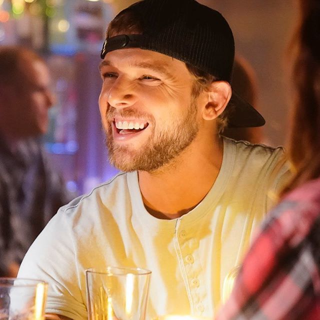 a man sitting at a table with two glasses in front of him and smiling for the camera