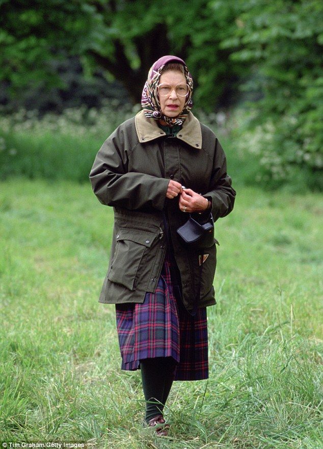 an older woman in a green jacket and plaid skirt is walking through the grass with her hand on her hip