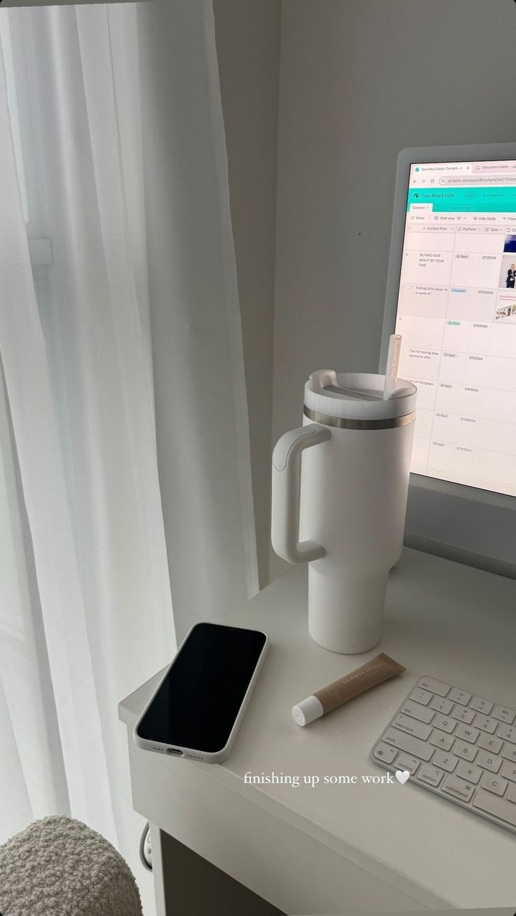 a coffee mug sitting on top of a desk next to a computer monitor and keyboard