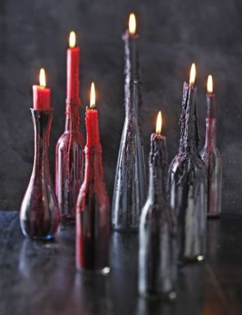 several bottles with candles in them are lined up on a table, one is red and the other is black