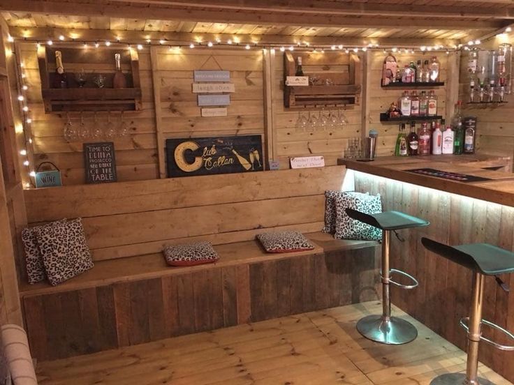 a small bar with stools and lights on the wall in a room that has wood paneling