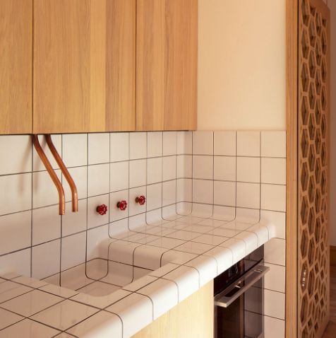 a kitchen with white tile and wooden cabinets