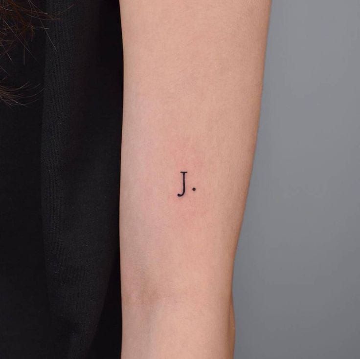 a small j tattoo on the arm