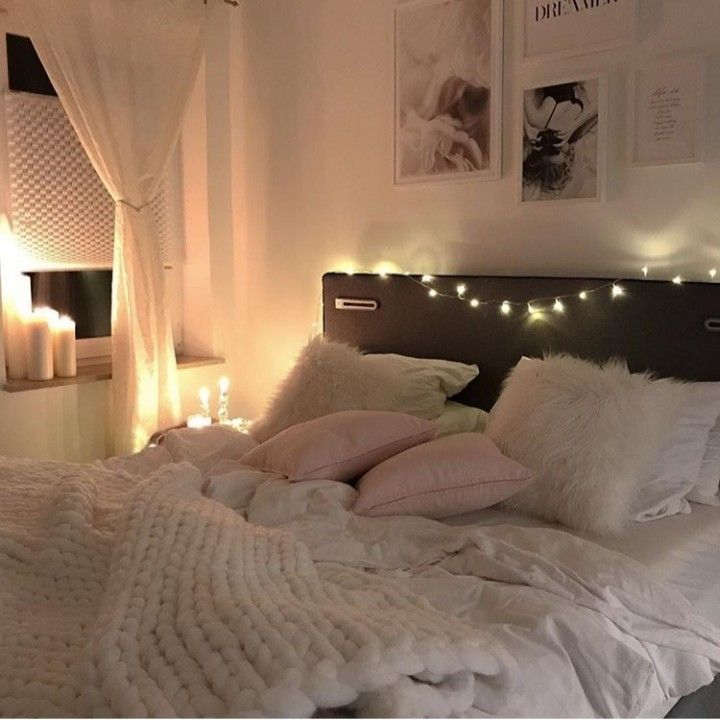 a bed with white blankets and lights on the headboard