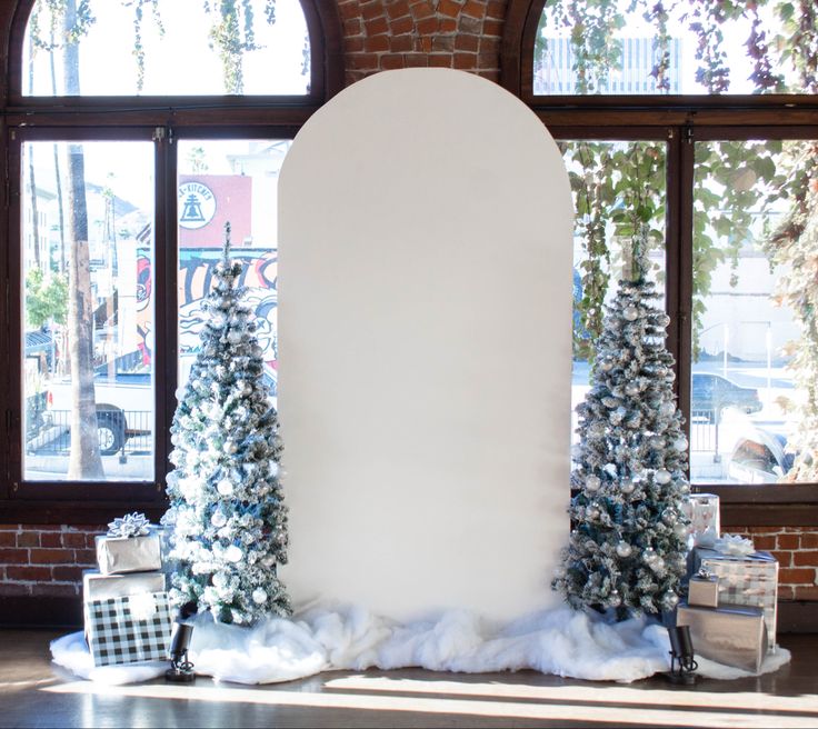 a large white sign surrounded by christmas trees and presents in front of a brick wall