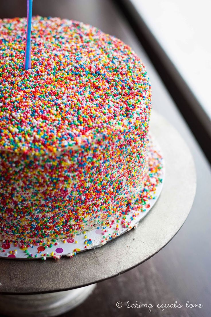 a birthday cake with sprinkles and a single candle on it's top