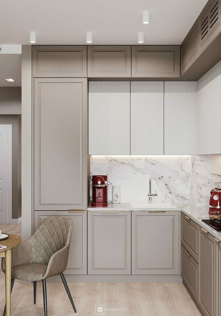 a modern kitchen with marble counter tops and gray cabinets, along with a dining room table