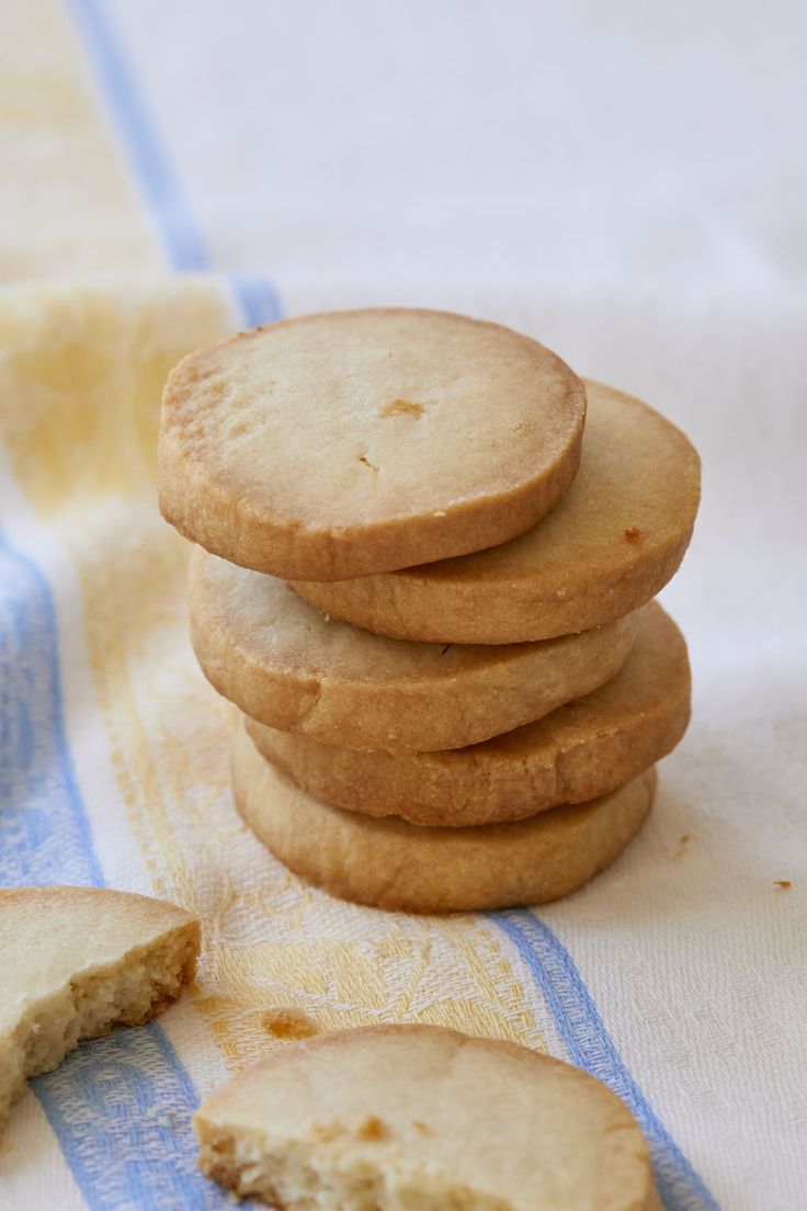 a stack of cookies sitting on top of a blue and white towel next to a slice of bread