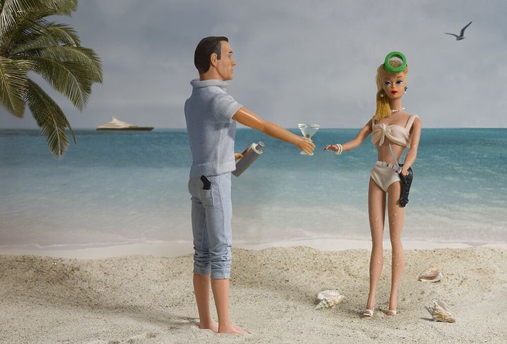 a man and woman standing on the beach with a bird flying over them, holding hands