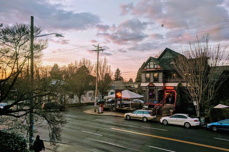 cars are parked on the street in front of a building at sunset or dawn,