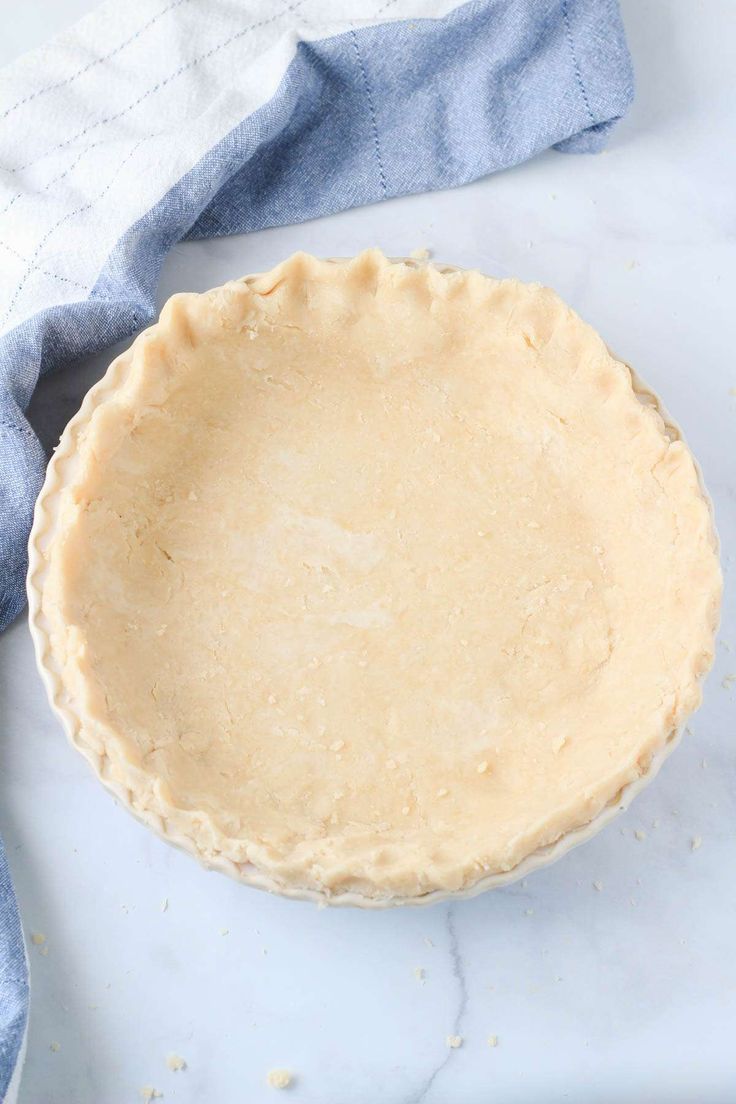 an uncooked pie sitting on top of a table next to a blue towel