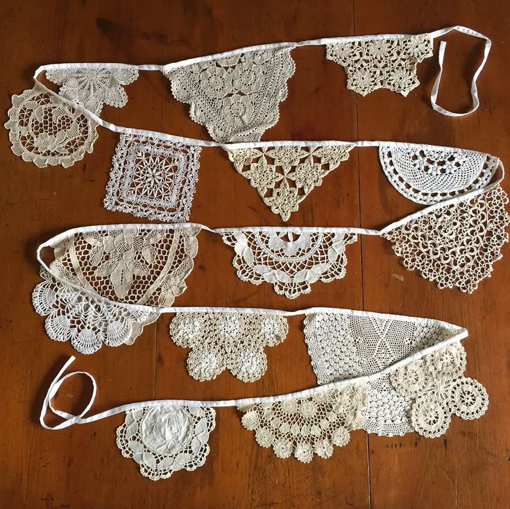 several white crocheted doily on a wooden floor with scissors and thread in the middle