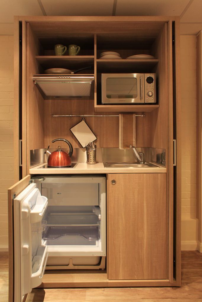 a small kitchen with an open refrigerator and microwave on the wall, next to a sink