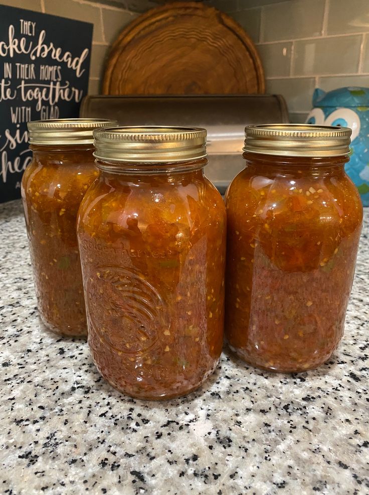 three jars filled with food sitting on top of a counter