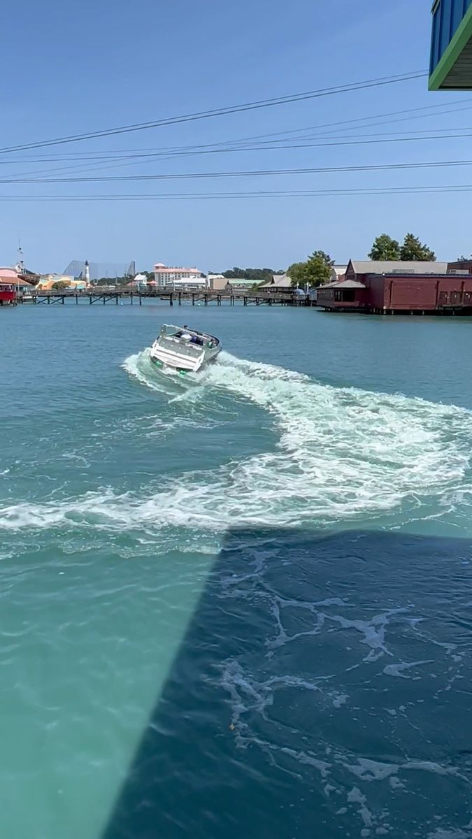 a boat is traveling through the water in front of a dock with houses and power lines