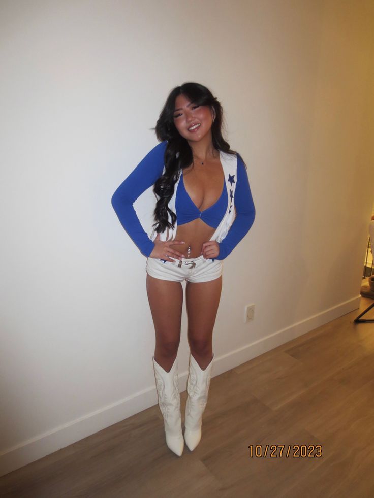 a woman in white shorts and cowboy boots posing for the camera with her hands on her hips