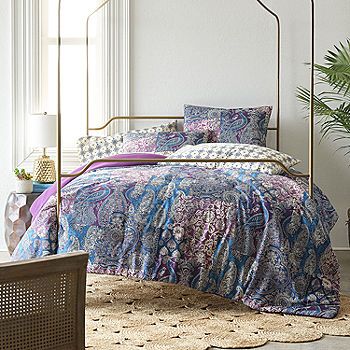 a bed in a bedroom with an iron frame and colorful bedspread on it