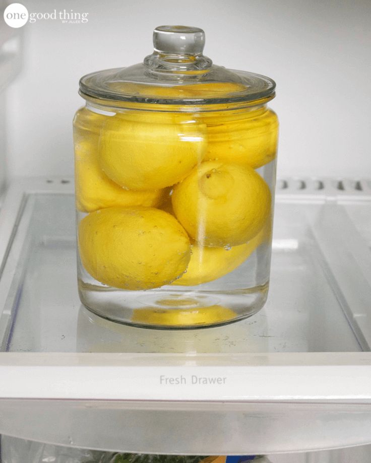 a glass jar filled with lemons sitting on top of a refrigerator