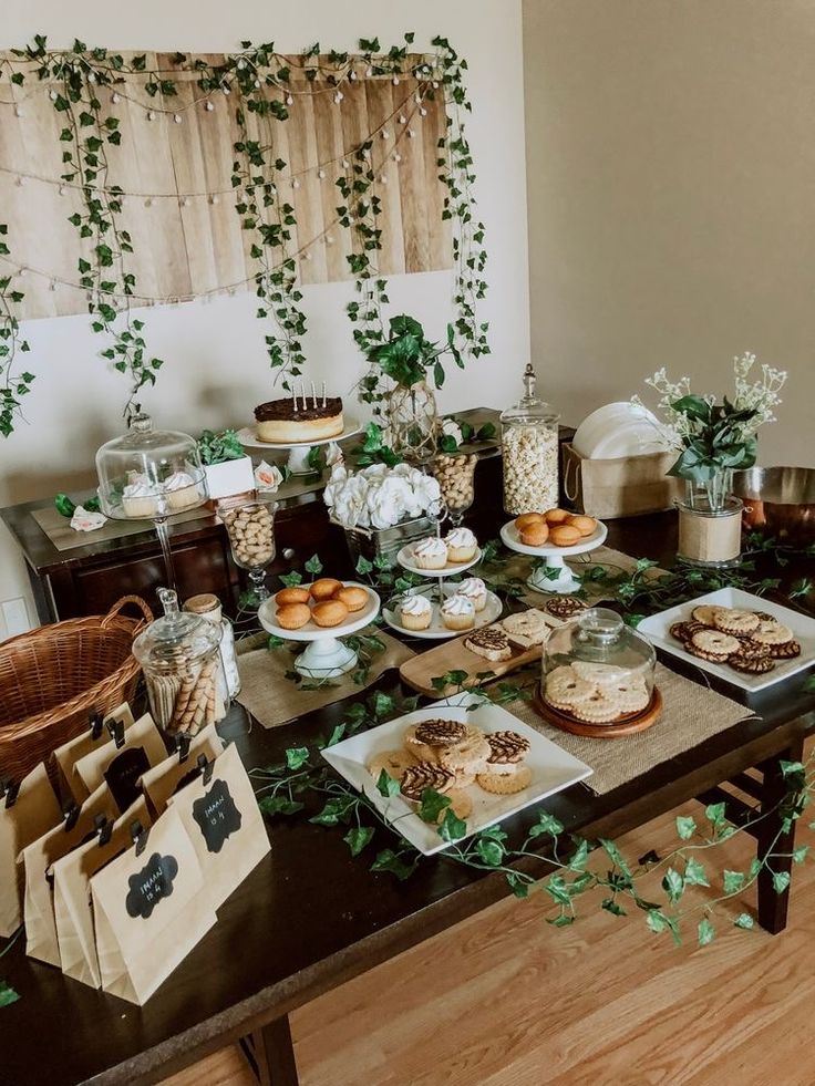 a table filled with lots of food on top of a wooden table covered in greenery