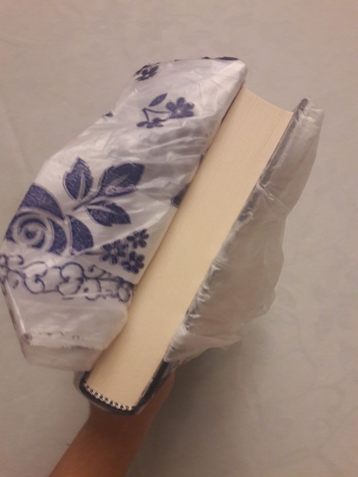 an open book wrapped in plastic on top of a hand