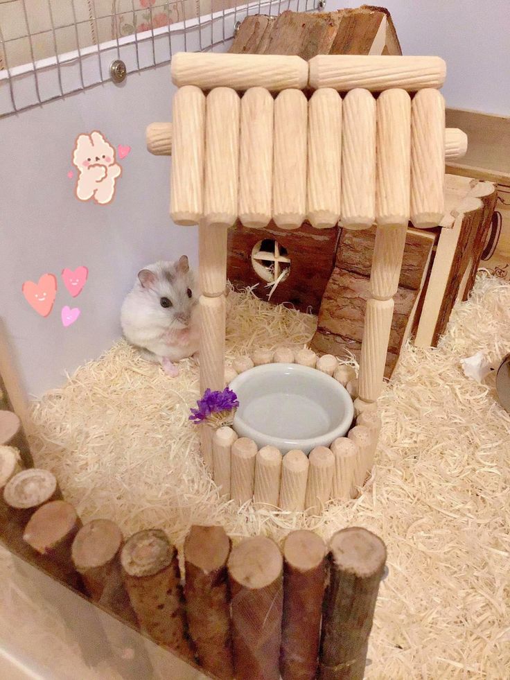 a hamster is sitting in the hay next to a wooden structure