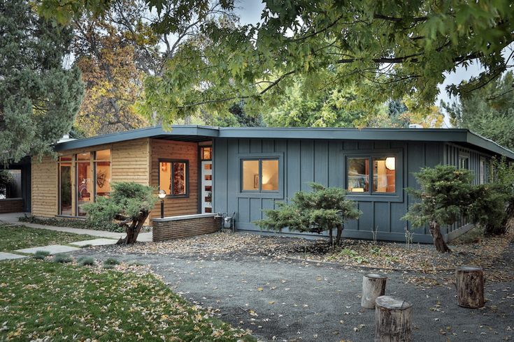 a blue house sitting in the middle of a yard with trees and bushes around it