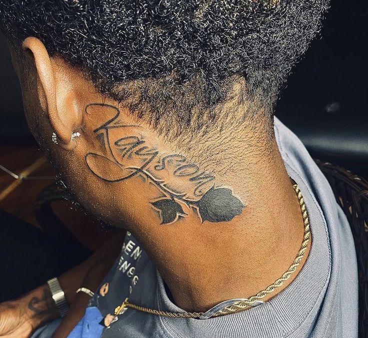 the back of a man's neck with his name tattooed on it and leaves